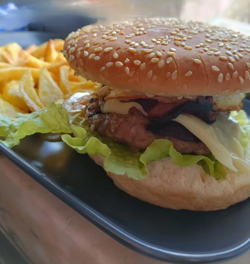 Delicious cheeseburger with bacon and caramelized onions, shot against a dark background. Perfect for food lovers.